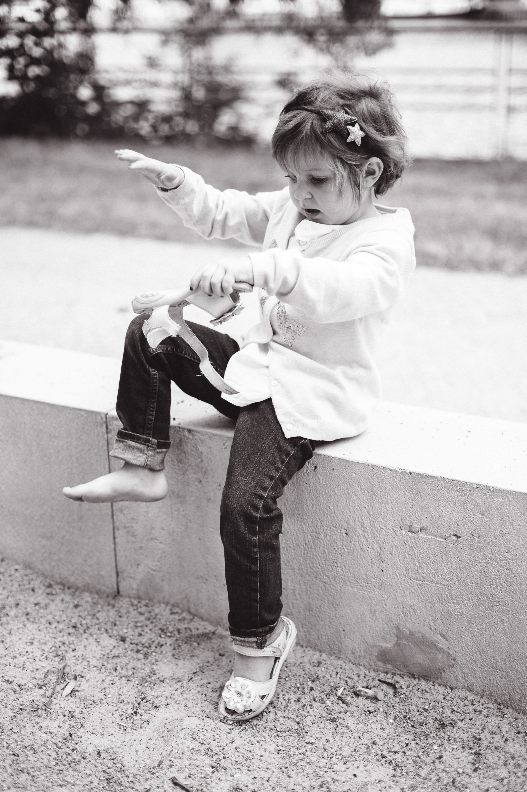 Mädchen schüttelt Sand aus ihren Sandalen