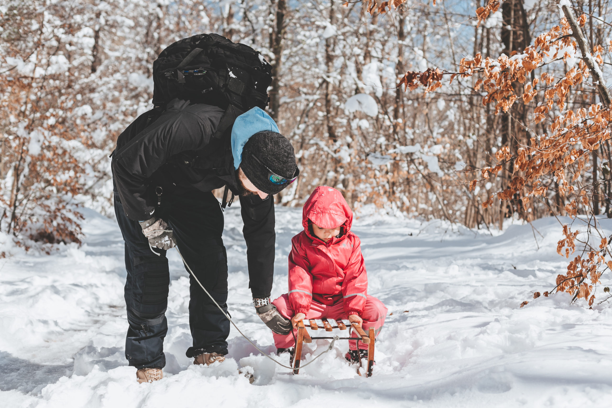 Papa mit Kind im Schnee. Schlittenfahren im Winter